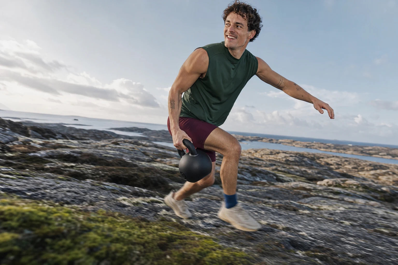 Mand træner med kettlebell ved kysten